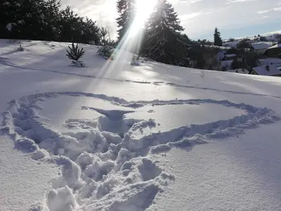 a heart in the snow with the sun in the background at Guest House Lorian in Madzhare