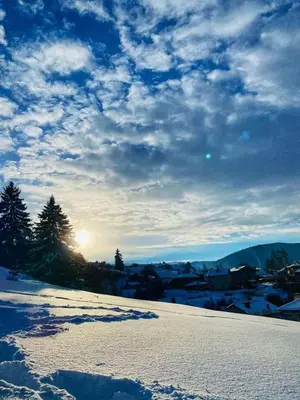 a snow covered field with the sun in the sky at Guest House Lorian in Madzhare