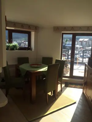 a dining room with a table and chairs and windows at Mountain Paradise 4 Apartments in Bansko