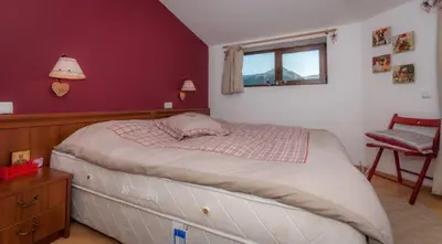 a bedroom with a large bed with a red wall at Mountain Paradise 4 Apartments in Bansko