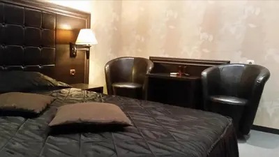 a bedroom with a bed and two chairs and a desk at Hotel Chamishki in Blagoevgrad