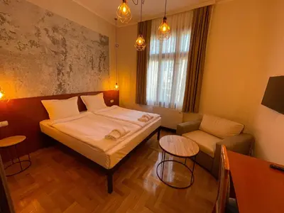 a bedroom with a bed and a chair and a table at СКЕРЦО SkerZZo Guest House in Plovdiv