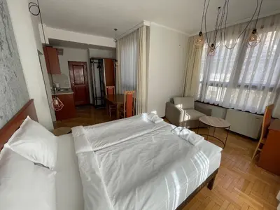 a bedroom with a white bed and a living room at СКЕРЦО SkerZZo Guest House in Plovdiv