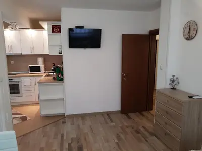 a kitchen with a white wall with a television on it at United Apartments in Sandanski