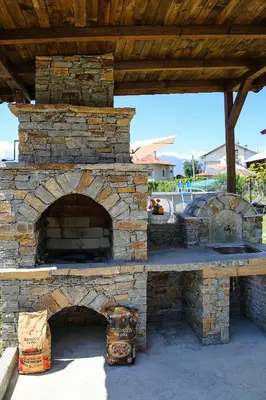 an outdoor brick oven with a wooden roof at Guest House Ognyanovo in Ognyanovo