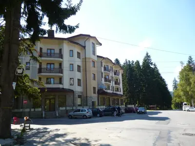 a large building with cars parked in a parking lot at Villa Park Apartment nr 216 in Borovets