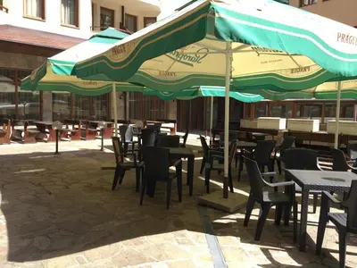 an outdoor patio with tables and chairs and umbrellas at Villa Park Apartment nr 216 in Borovets