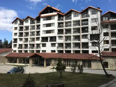 a large white apartment building with a parking lot at Rivendell Apartments Borovets Gardens complex in Borovets