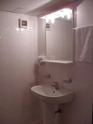a white bathroom with a sink and a mirror at Hotel Velbazhd in Kyustendil