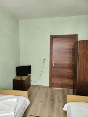 a room with two beds and a door and a television at Apartment Lachevi in Sandanski