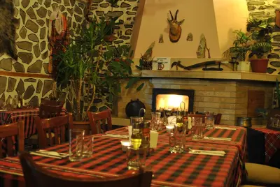 a restaurant with tables and chairs with a fireplace at Family hotel Gradina in Ognyanovo