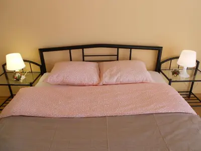 a bedroom with a bed with a pink bedspread and two lamps at Апартамент Мур in Sofia