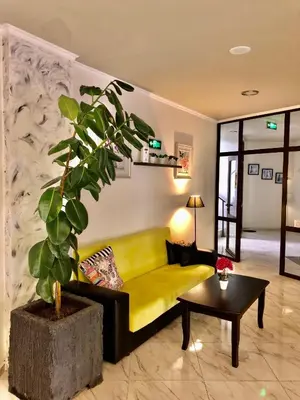 a living room with a yellow couch and a plant at Hotel Ostrova in Plovdiv