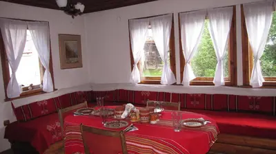 a dining room with a table and a tower in the window at Villa Lyutovi Holiday Home in Koprivshtitsa