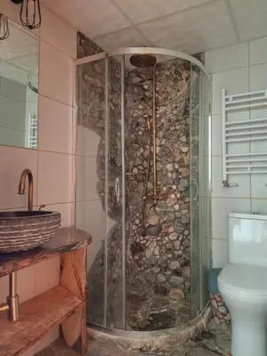 a bathroom with a shower with a stone wall at Villa Lyutovi Holiday Home in Koprivshtitsa