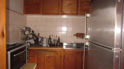 a kitchen with wooden cabinets and a stainless steel refrigerator at Villa Lyutovi Holiday Home in Koprivshtitsa