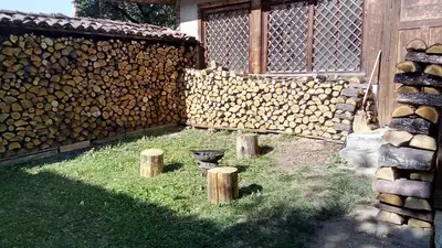 a fence with a bunch of logs next to a yard at Villa Lyutovi Holiday Home in Koprivshtitsa