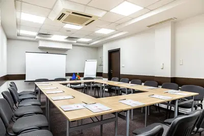 a conference room with tables and chairs and a whiteboard at Sofia Palace Hotel by HMG in Sofia