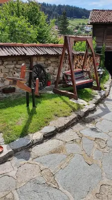 a wooden bench sitting on the grass in a yard at Guest rooms Colorit in Koprivshtitsa