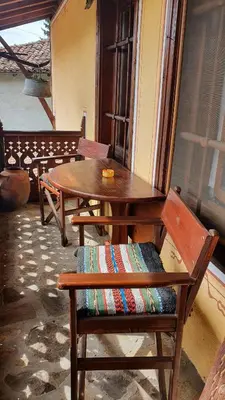 a wooden bench with a table and a chair at Guest rooms Colorit in Koprivshtitsa