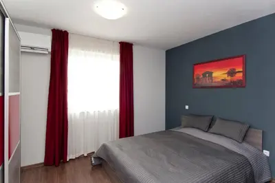 a bedroom with a bed and a window with red curtains at Sofia Top Lux Apartment in Sofia