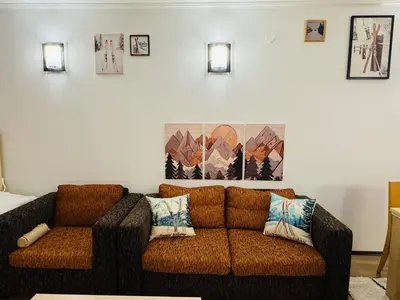 a living room with a brown couch and some pictures on the wall at Stenata Huge Ski To Door Apartments in Pamporovo
