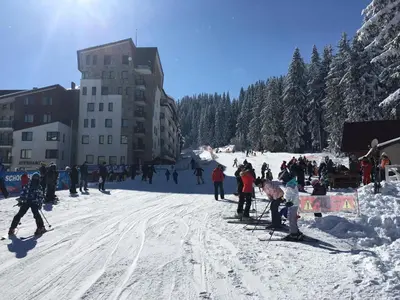 a group of people skiing on a snow covered slope at Stenata Huge Ski To Door Apartments in Pamporovo