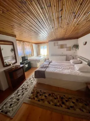 a large room with two beds and a wooden ceiling at Guest House Detelina in Devin