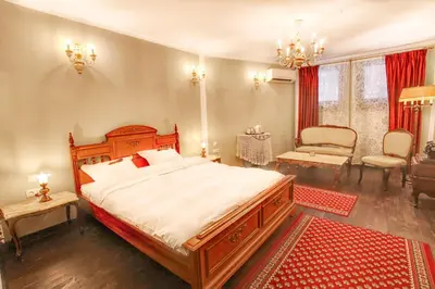 a bedroom with a large bed and a chair at Hotel Evmolpia in Plovdiv