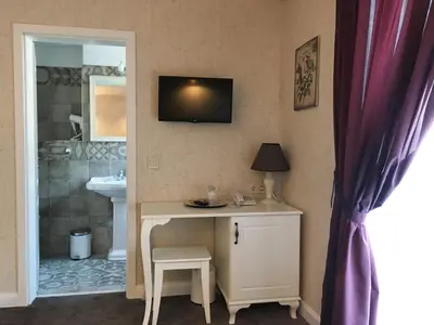 a bathroom with a sink and a desk with a television on the wall at Family Hotel Agoncev in Sofia