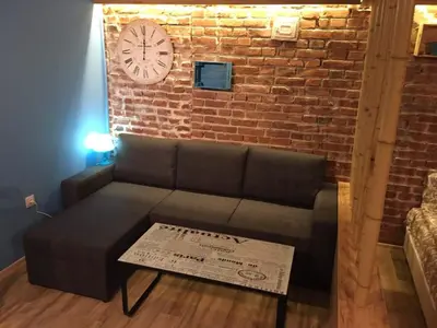 a couch in a room with a brick wall and a clock at City Garden Studio in Plovdiv