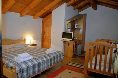 a bedroom with a bed and a desk with a television at Trenchova Guest House in Bansko