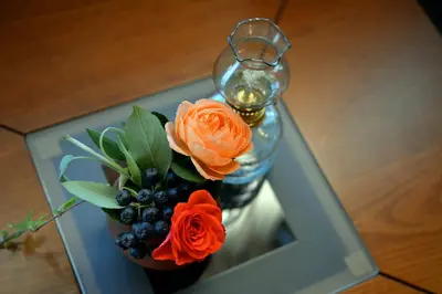 a vase with orange roses and berries on a table at Trenchova Guest House in Bansko
