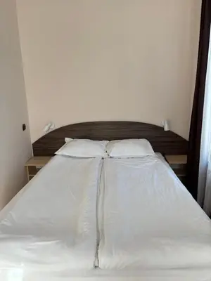 a bed with white sheets and pillows in a room at Apartments Black Horse in Pamporovo