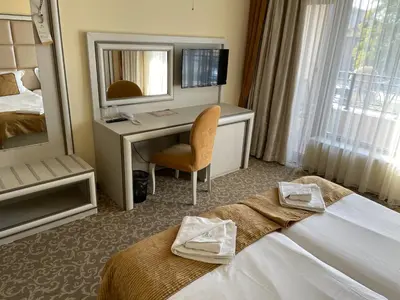 a hotel room with a bed and a desk with a mirror at Hotel Forum in Pazardzhik