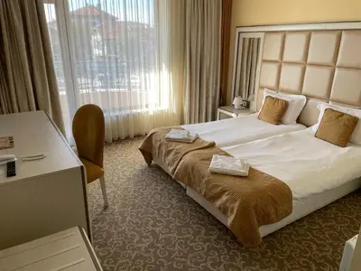 a hotel room with a large bed and a desk at Hotel Forum in Pazardzhik