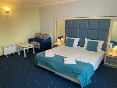 a hotel room with a large bed and a chair at Hotel Forum in Pazardzhik