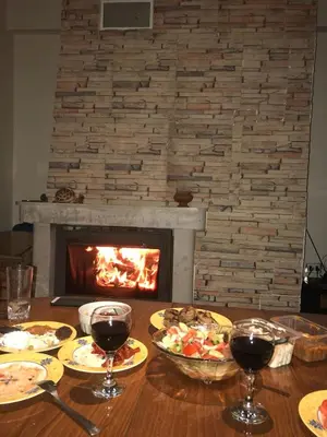 a table with food and wine glasses and a fireplace at Manastira 2 apt Emo Pamporovo in Pamporovo
