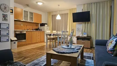a living room with a couch and a table in a kitchen at Ramada 2 Boutique Apartment near Ski Road in Bansko