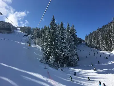 a group of people skiing down a snow covered slope at Ramada 2 Boutique Apartment near Ski Road in Bansko