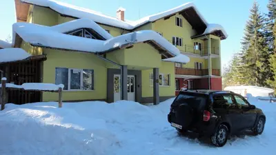 a car parked in the snow in front of a house at Бунгала Говедарци in Govedartsi