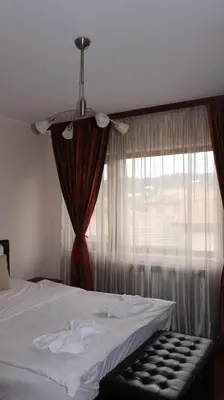 a bedroom with a white bed and a window at Valevitsata Guesthouse in Razlog