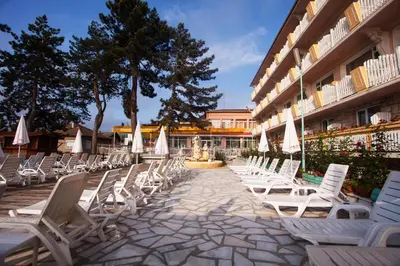 a row of chairs and a fountain in front of a building at Balneo & SPA Hotel Aura in Velingrad
