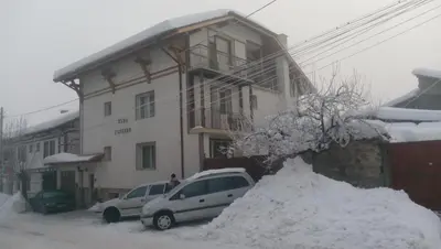 two cars parked in front of a house in the snow at Guest House Garbevi in Dobrinishte