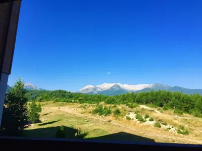 a view of snow capped mountains from a window at PM Mountain View Fireside Retreat Bansko in Bansko