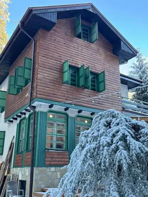 a house with green windows and a pile of snow at Villa Adis with Hot Pool & Jacuzzi by BookVillaBG in Borovets