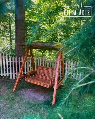 a wooden swing sitting in front of a tree at Villa Adis with Hot Pool & Jacuzzi by BookVillaBG in Borovets