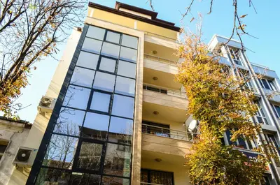 a tall building with glass windows and trees at Main Street Apartment in Sandanski