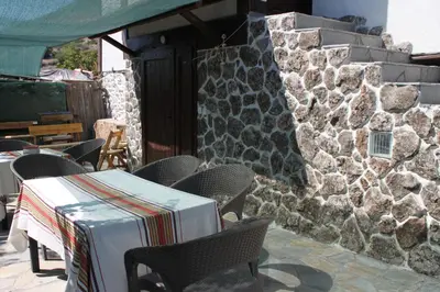 a patio with chairs and a table and a stone wall at Eco Village Under the Cliffs in Ilindentsi