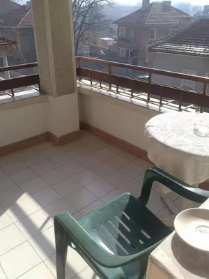 a green chair sitting on a balcony with a table at Bonbon Guest House in Panagyurishte